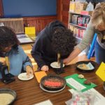 Two children work on a project with their teacher.